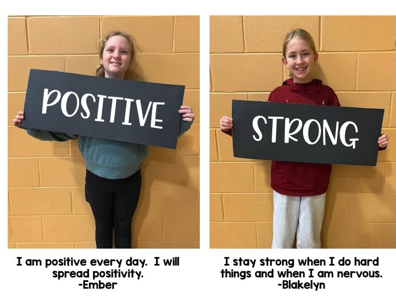 students holding signs saying 'positive' and 'strong'. Text beneath says 'I will be positive every day. I will spread positivity' - Ember. and "I stay strong when I do hard things and when I am nervous" - Blakelyn