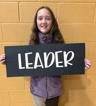 student holds a sign that says 'leader'